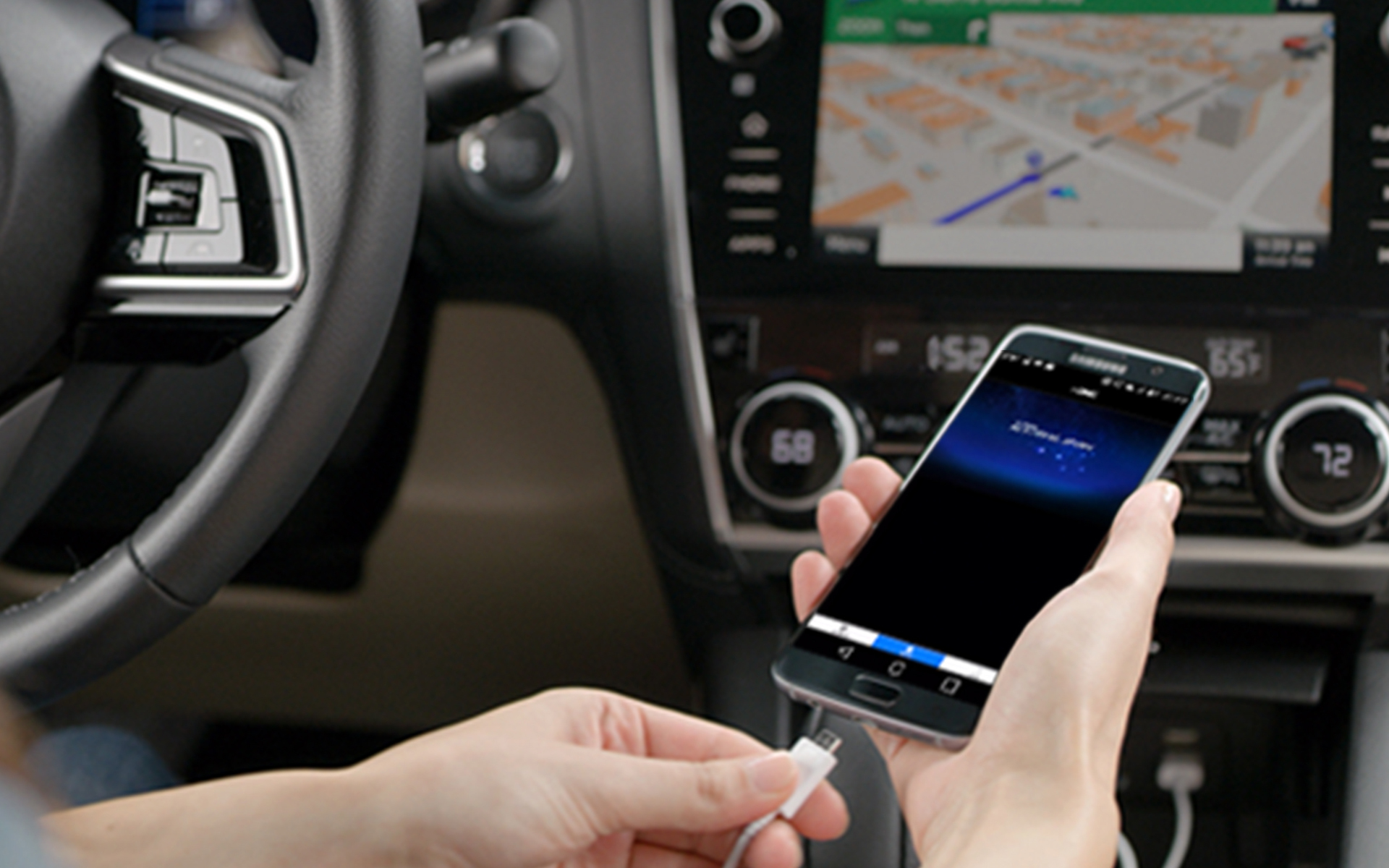 Hand holding a smartphone with the MySubaru app shown on the screen.