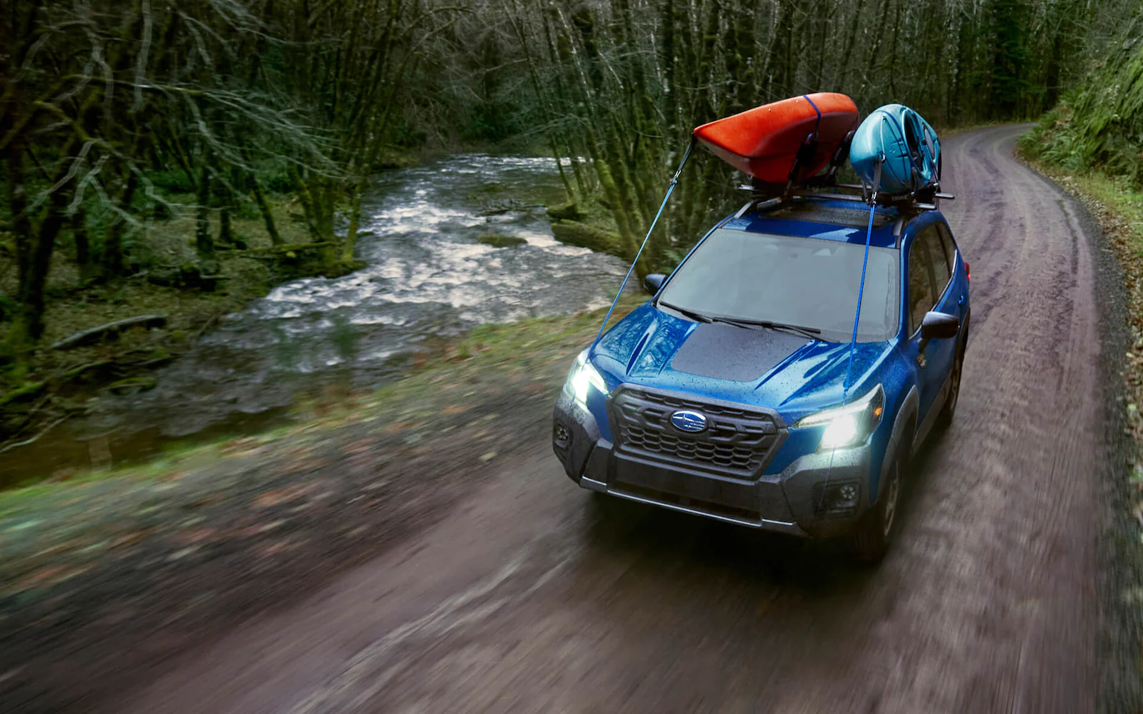A 2022 Subaru Forester Wilderness driving along a dirt road in the forest.