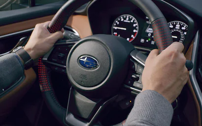 Man's hands on the steering wheel of a Subaru Legacy