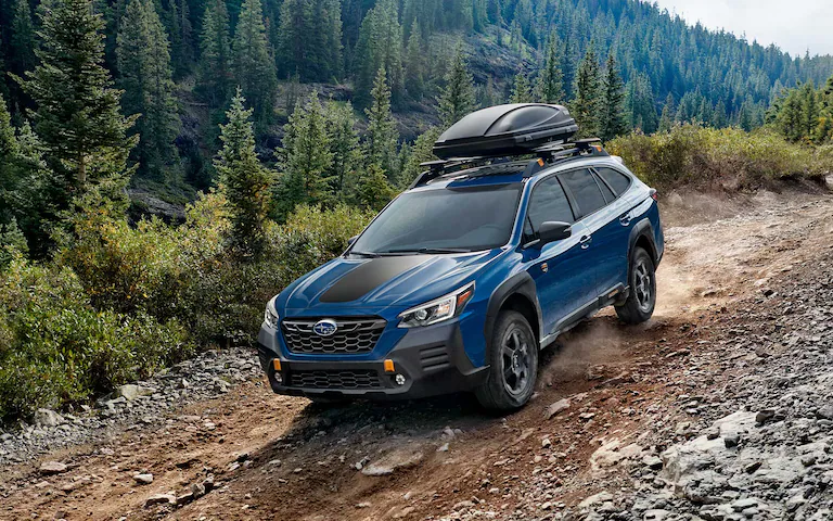 Top front view of a blue 2022 Subaru Outback Wilderness driving down a rocky incline