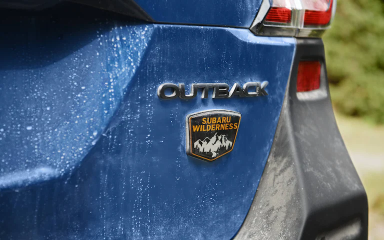 Outback and Subaru Wilderness badges on the back of a blue vehicle