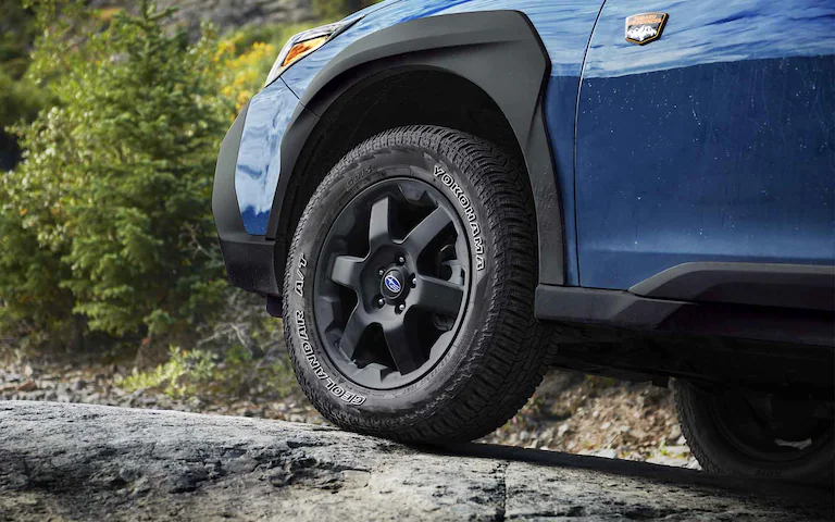 Wheel and tire on a Subaru Outback Wilderness driving on a rock