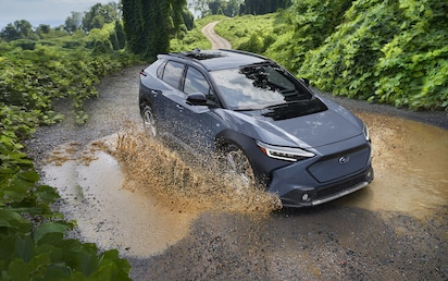 A 2023 Solterra driving through a mud puddle on a dirt road.