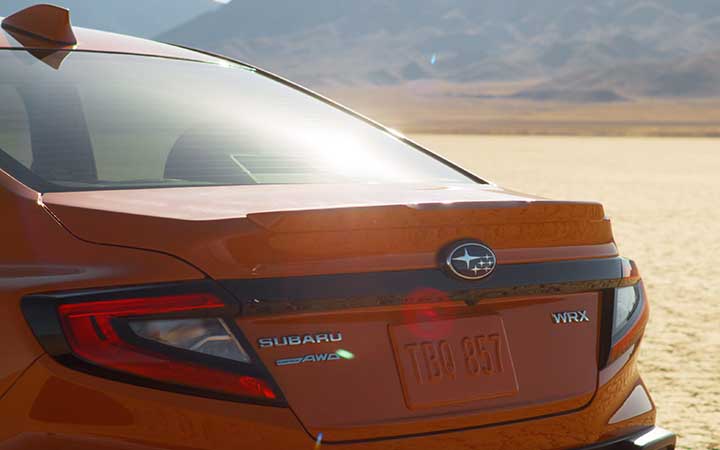 Close up back view of an orange 2022 Subaru WRX parked in the desert