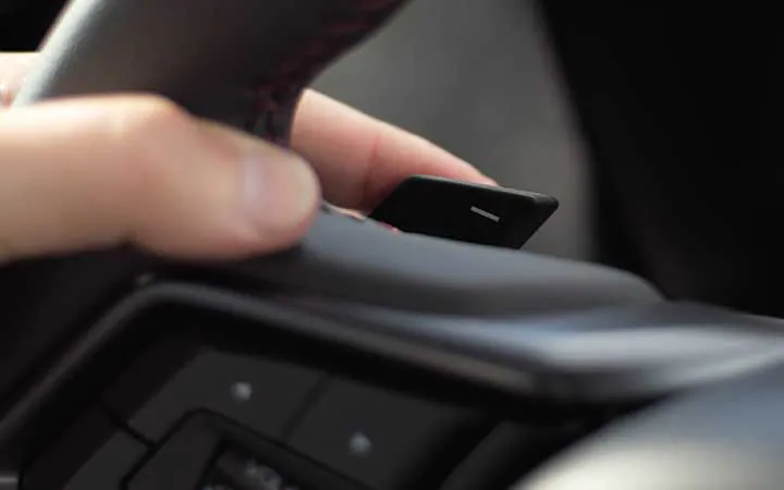 Close up of fingers wrapped around the steering wheel of a Subaru WRX